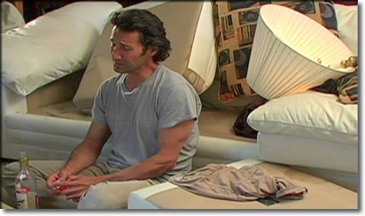 Photo a man sitting on living room floor amid damaged furnishings.