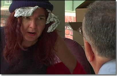 Still frame from video picturing a woman with tin foil on head.