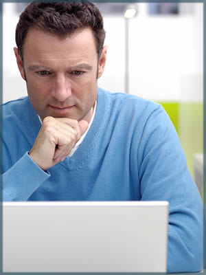 a man looking at a laptop in deep thought