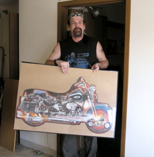 Man proudly holding a large picture of a Harley Davidson motorcycle.
