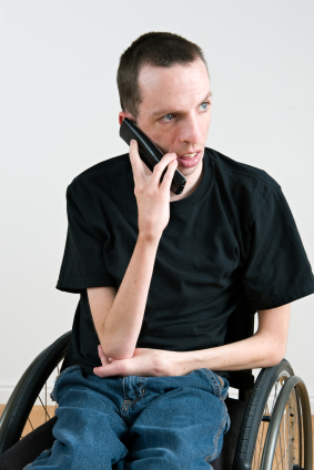 Man seated in a wheelchair talking on phone.